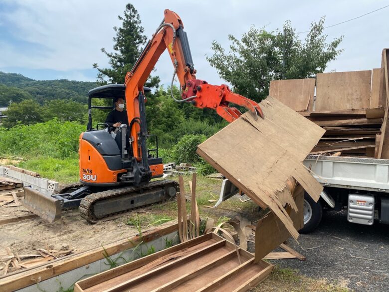 パネルをユンボでダンプに積む